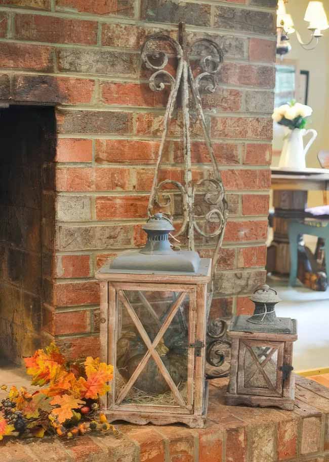 This large wooden lantern has a small green pumpkin inside, and the vine-like metal piece behind it is a clever way to add height to the whole fall decor scene.