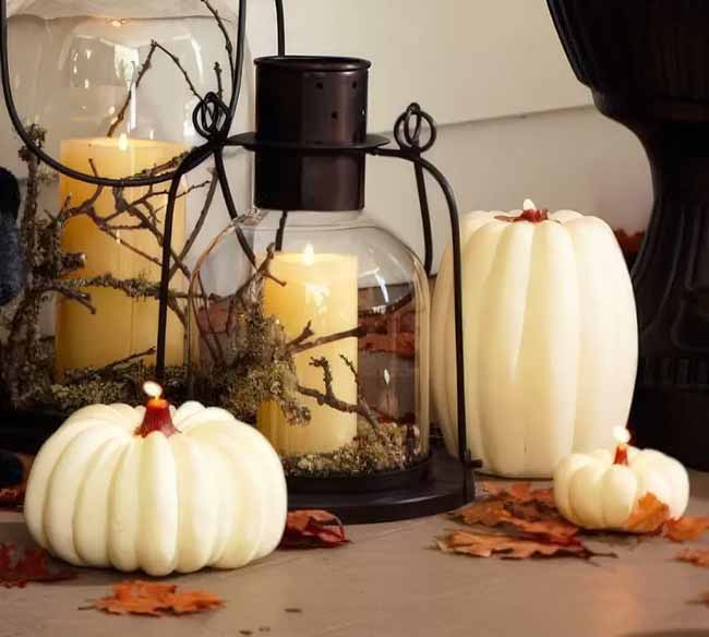 I love this idea for a spooky, yet chic look—the large glass globe lanterns are filled with thick candles, moss, and tangled, dark twigs. The white gourd pumpkins scattered around the base are a simple contrast that works great for Halloween or early fall.