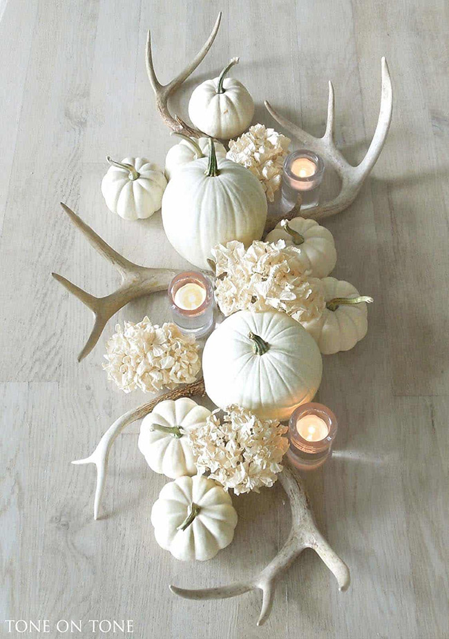 Mixing a white pumpkin with things like deer antlers and candles creates a stunning centerpiece for a table. The combination of natural and soft elements feels both rustic and elegant.