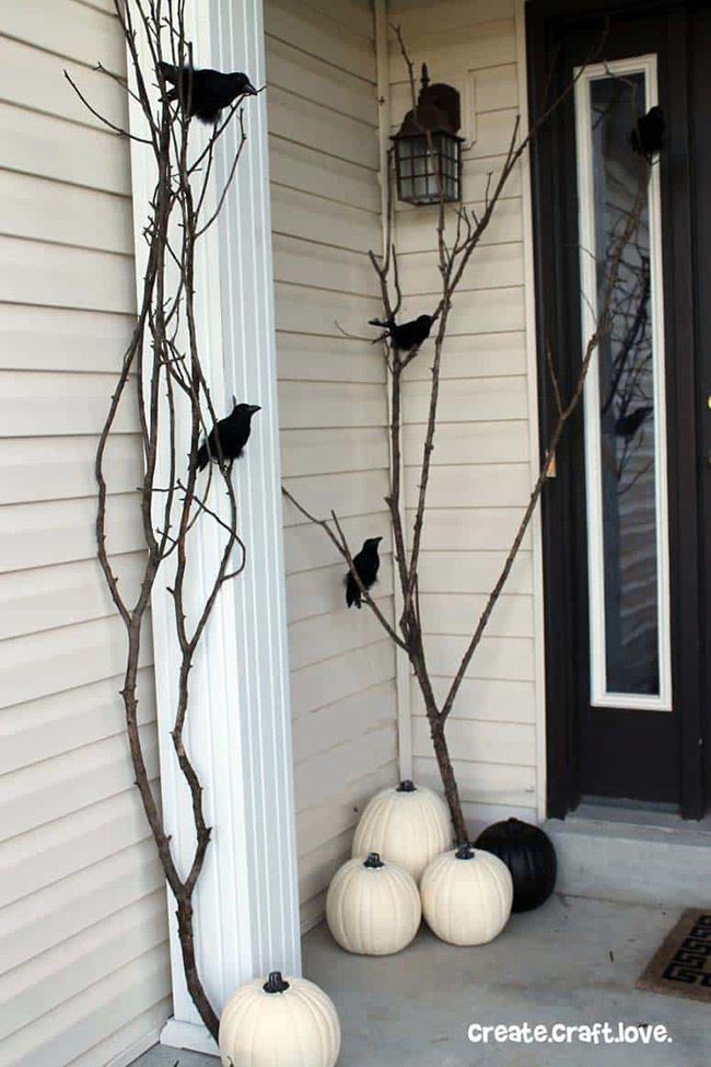 Wow, this is a spooky but cool look! Those tall, dark, bare branches with the black crows make a great contrast to the three plain white pumpkins sitting by the door. It's a simple way to use the white pumpkin for a slightly scary Halloween feel.