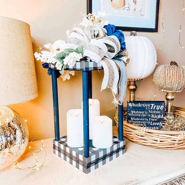 What a cool, different look! The blue buffalo check base and columns make this white-candle lantern feel modern, while the big bow and white flowers on top still make it cozy.