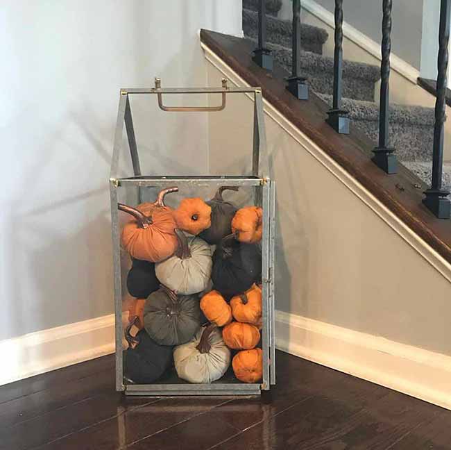 This is not a candle lantern, but it's a great floor idea! This huge, clear metal box is filled right up with soft fabric pumpkins in orange, gray, and white, making a fun, easy decoration for next to the stairs.