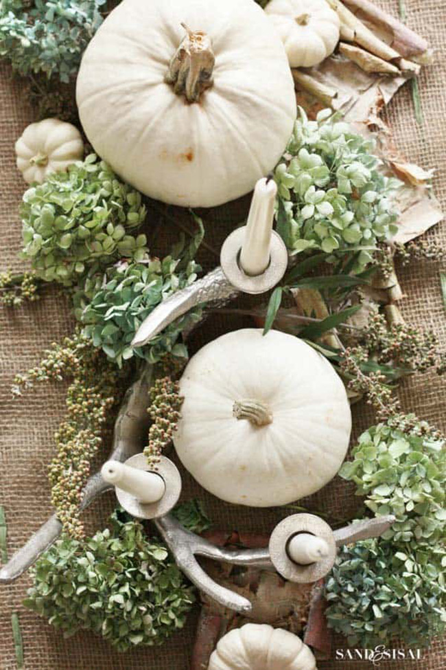 This centerpiece shows how beautiful it is to mix different textures together. The smooth skin of the white pumpkin looks amazing next to soft hydrangea flowers and unique, silver-painted antlers that double as candle holders.