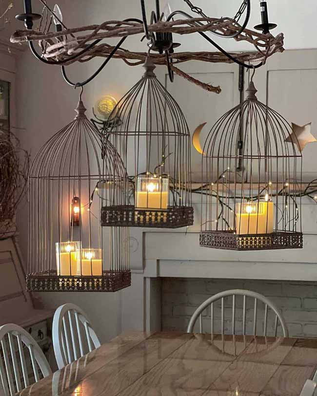 These birdcages hanging over the table are a fun, clever way to use candlelight; the tiny fairy lights on the twigs add a soft sparkle. This setup is perfect for a rustic, unique fall dining style.