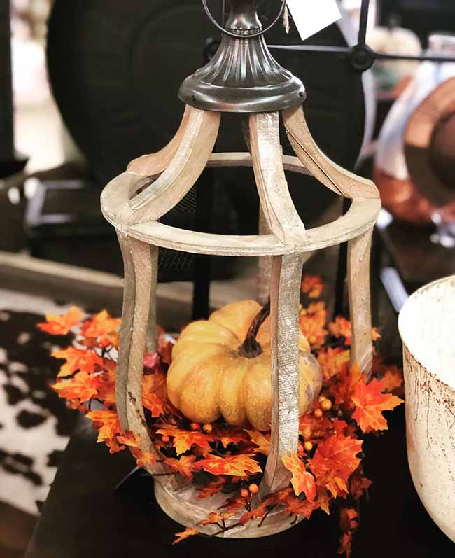 This light wood lantern has simple curved sides that perfectly frame the big orange pumpkin inside. Piling a thick layer of bright orange fall leaves around the base is an easy, great way to fill the space.