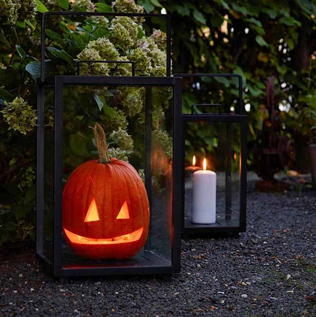 This is a great, modern twist on a classic Jack-o'-lantern—a carved pumpkin set inside a big black glass lantern on the ground. Having the plain white candle next to it creates a simple, fun welcome light for the walkway.