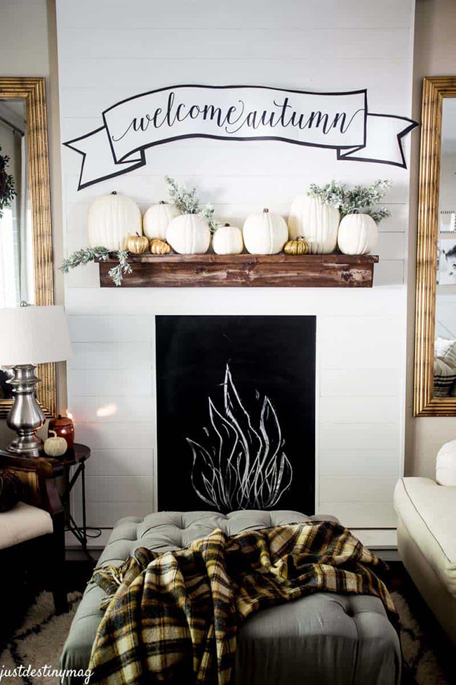Arranging a long line of white pumpkins across the shelf provides a clean, impactful display that celebrates the season in a sophisticated way.