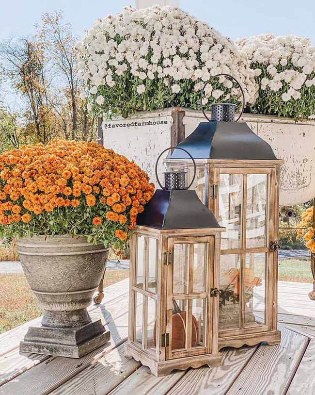 These two wood and black metal lanterns are perfect for a farmhouse porch look, sitting next to a huge urn of bright orange mums. The contrast of the rustic wood and the bright flowers makes for a gorgeous autumn welcome.