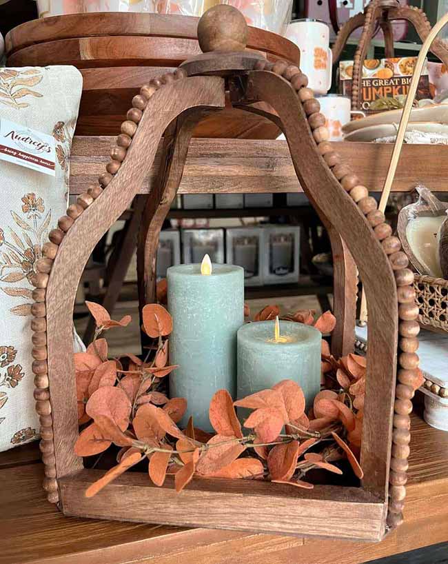 This wooden lantern has a beautiful beaded arch design and holds two soft pale-blue candles. The burnt-orange fall leaves tucked around the candles are a simple, modern way to add autumn color to a unique piece.