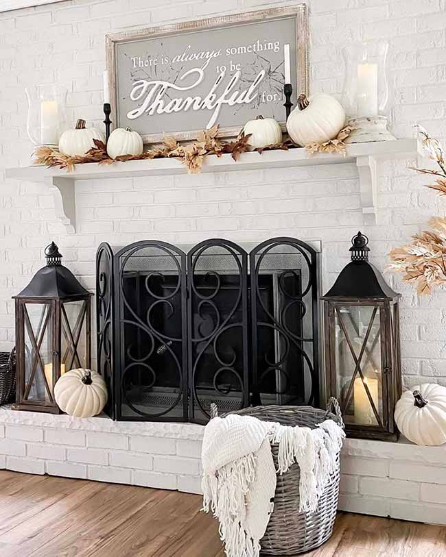 The two big black metal lanterns on the white brick hearth, next to the scrollwork fireplace screen, give this area a clean, elegant look. The contrasting white pumpkins on the floor and the 