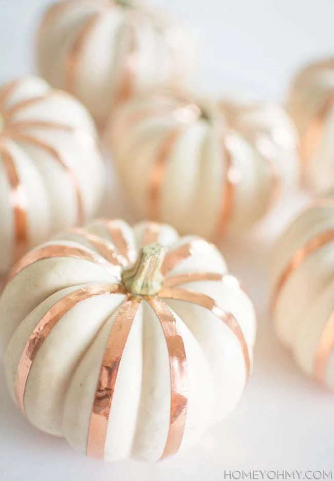 These small white pumpkins are so cute and modern! The little strips of shiny rose gold tape going down the sides look super clean and stylish. It shows you can make a white pumpkin look really glamorous with just a little effort.