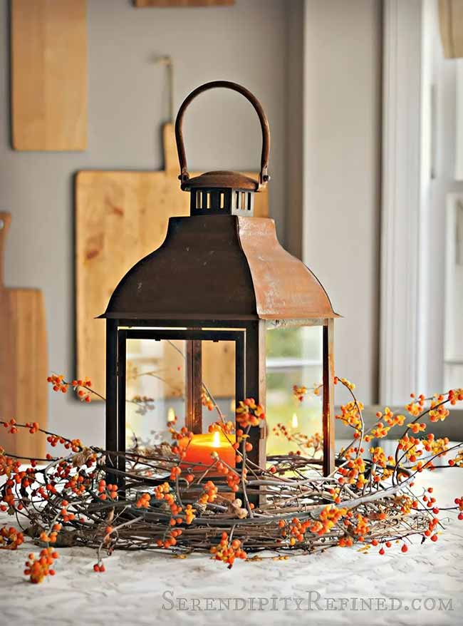 This tall, reddish-brown metal lantern has a great, aged look to it. Placing it inside a wreath made of tiny orange berries and twigs makes it a perfect, simple fall centerpiece for the kitchen table.