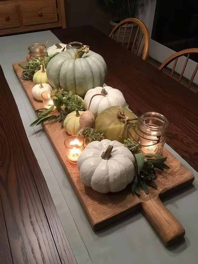 A bunch of soft-colored pumpkins and some little candles on a wooden board make for a super cozy and rustic fall table centerpiece.