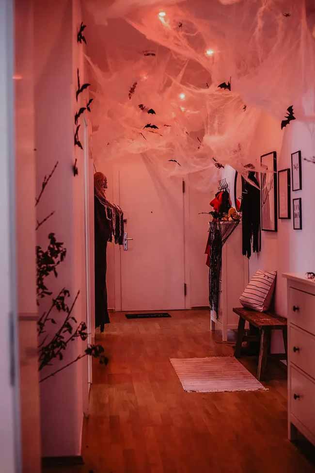 Covering the whole ceiling in spiderwebs and adding a red light is a simple but super spooky Halloween idea. It makes the whole hallway feel creepy.