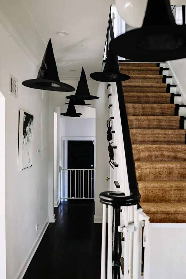 Just hanging a few witch hats in a hallway is a really easy Halloween decoration. It looks so good against the white walls and black railing.