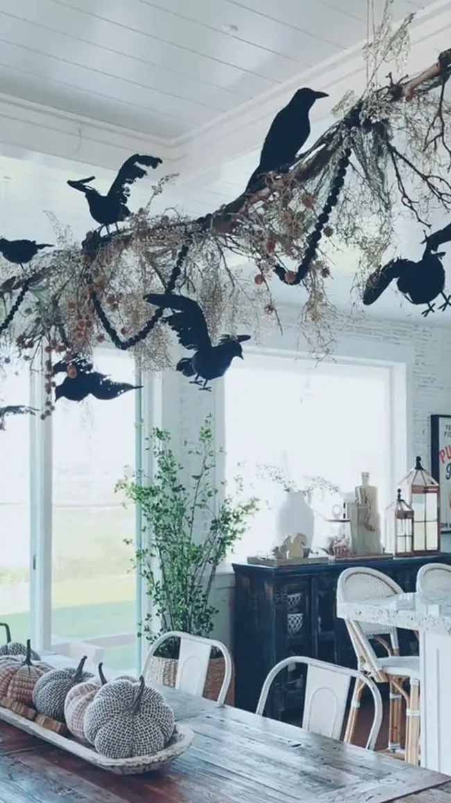 Hanging a big, spooky branch with crows over the table is such a cool idea. This makes a perfect Halloween centerpiece for a dinner party.