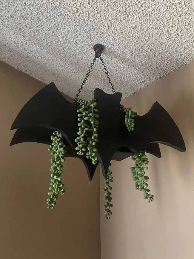What a creative idea! It's a bat-shaped planter hanging from the ceiling. This is a cool Halloween decoration that you could even leave up after the holiday.