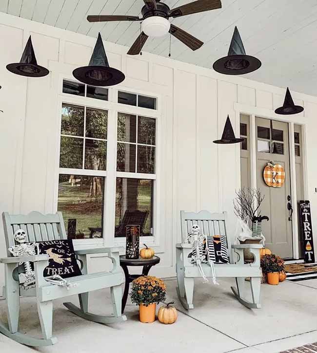 This is such a welcoming Halloween porch. The skeletons in the chairs are funny, and the floating witch hats on the ceiling add the perfect spooky touch.