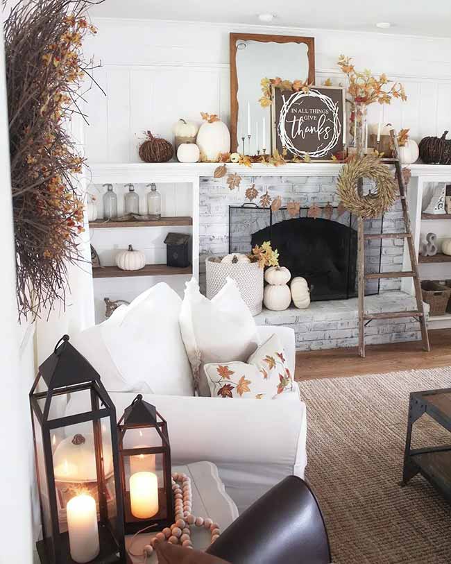 Look at all the cute white and brown pumpkins on the painted brick fireplace! The 'In all things give thanks' sign is great for the holiday season. The ladder and the big twig wreath on the side add a nice rustic touch.