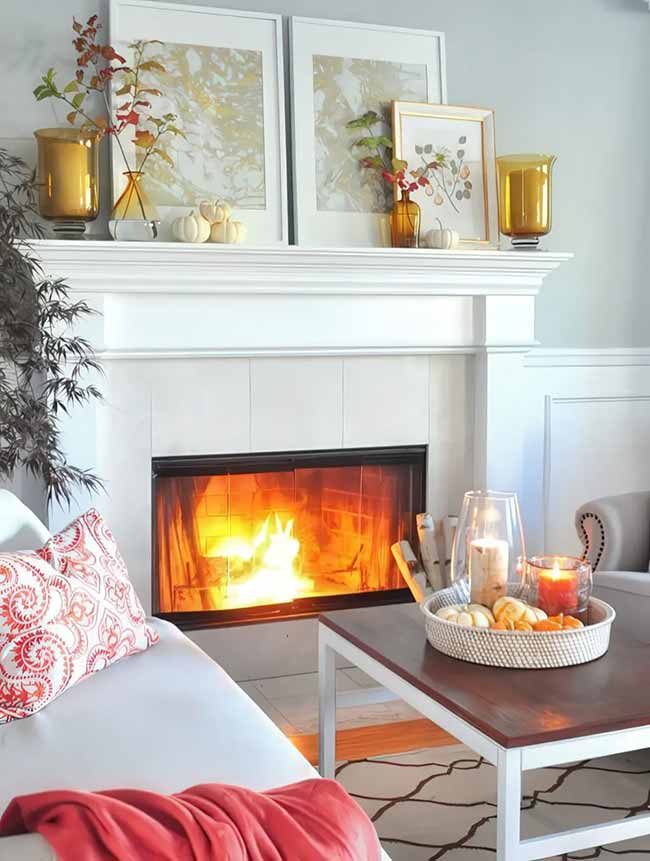 This fireplace looks so inviting with the fire glowing and the orange throw nearby. The small white pumpkins on the tray and the rich golden vases on the mantel add simple elegance. It's a clean, modern way to decorate for the fall.