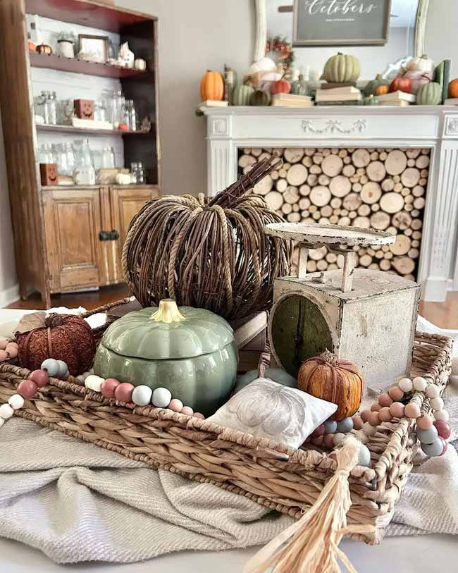 The natural wood stack in the empty fireplace opening is so clever and cozy. I love the big, braided pumpkin and the dusty green ceramic one on the woven tray. The pale pink and brown beads give this whole setup a very soft, unique look.