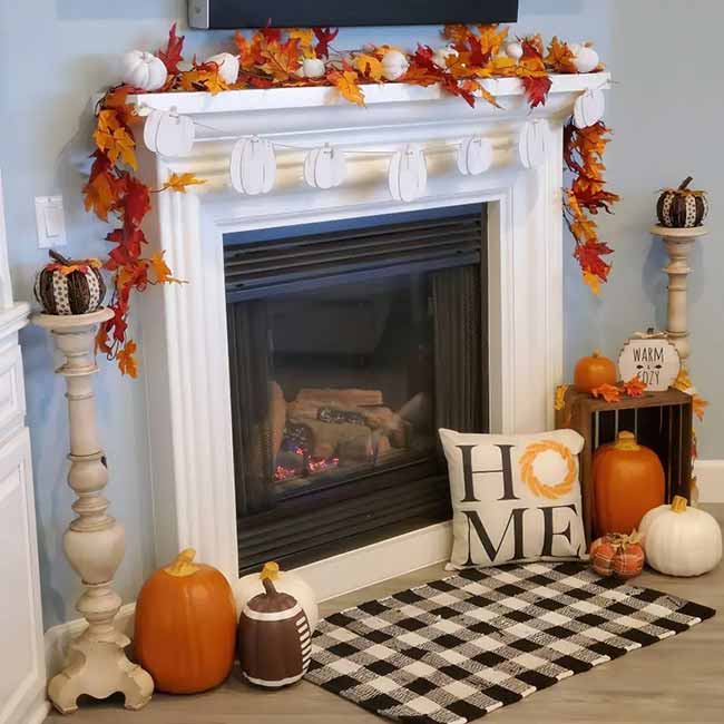 This is a fun, bright setup with a focus on Halloween and Thanksgiving! The garlands of leaves and the white pumpkin banner on the mantel are very festive. The black and white checked rug makes the orange pumpkins stand out nicely.