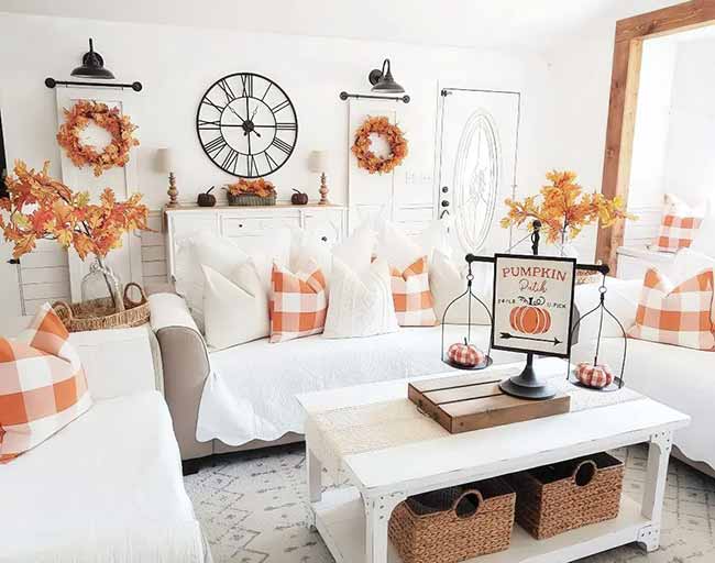 The farmhouse style in this room is so clean and cute with the white furniture. The orange buffalo check pillows and the twin wreaths on the wall are a fun, repeating pattern. The big round clock ties the whole rustic look together.