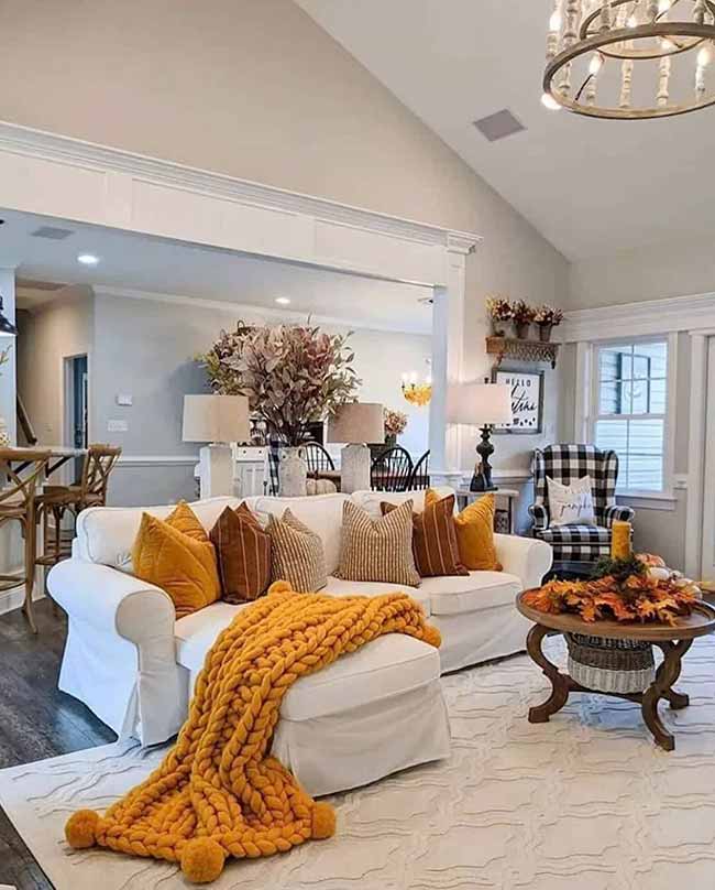 That super chunky orange blanket is the first thing you see and it looks so warm. The bright orange pillows mix well with the darker brown ones on the white couch. It's a perfect look for being cozy, and I like the checkered chair in the corner.