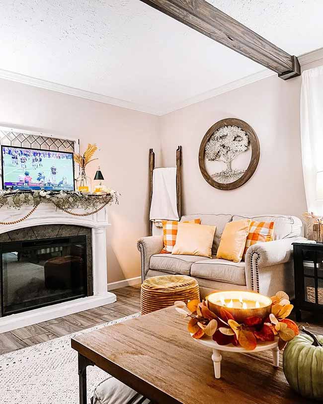 The rough wooden beam on the ceiling gives this room a rustic feel. The white fireplace is decorated simply with a beaded garland and a small fall arrangement. A nice little seating area for enjoying a fire and a football game.