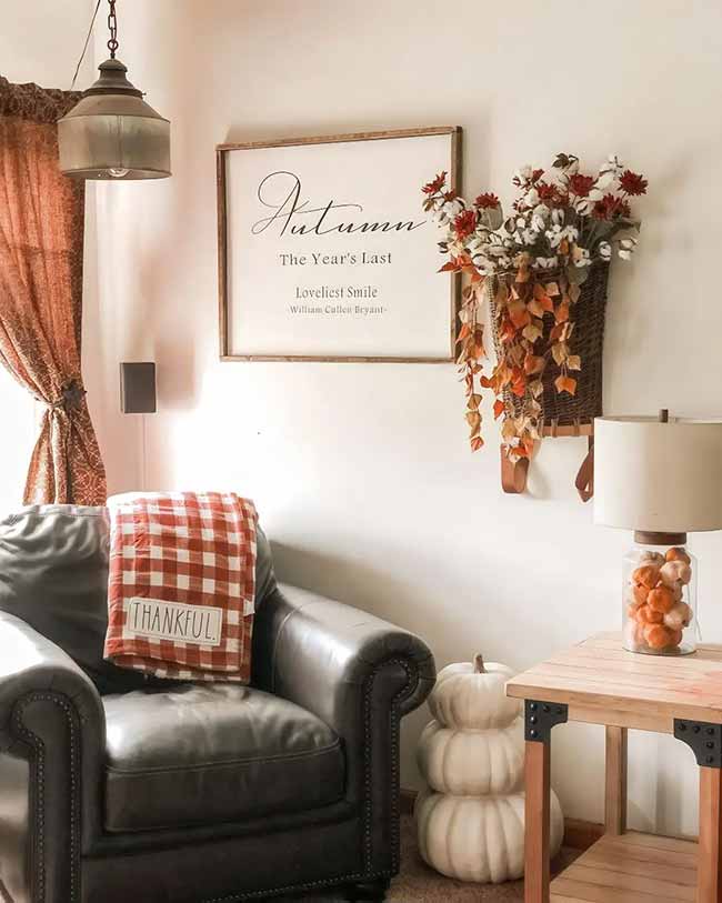 That dark leather chair looks so comfy for reading. The big white sign on the wall has a beautiful autumn quote. I love how the little glass jar is filled with mini white pumpkins next to the chair.