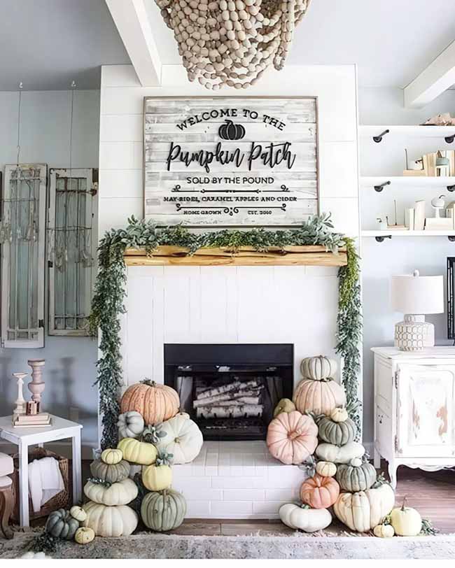 The two piles of pastel pumpkins framing the fireplace look like a colorful waterfall! The large 'Welcome to the Pumpkin Patch' sign above the mantel is a great centerpiece. The light blue shiplap and the shell chandelier are a nice contrast to the rustic wood.