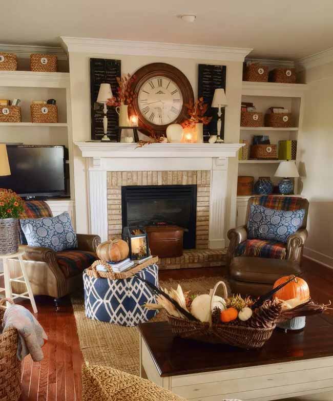 The built-in shelves on both sides of the fireplace are full of baskets and fall decor. The leather chairs with the plaid throws are super cozy and inviting. The huge clock above the mantel is a great focal point.