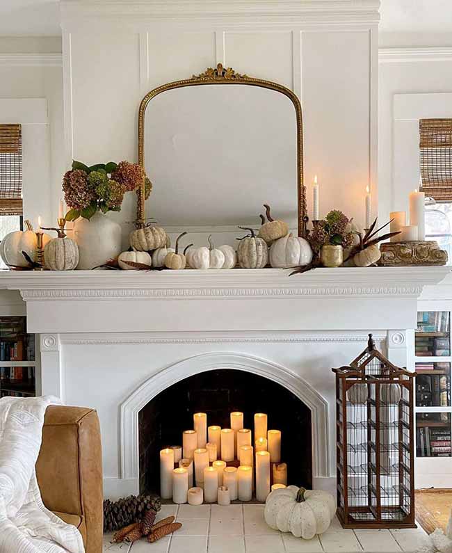This is a stunning display of white on a grand scale! The mantel is covered in different sizes of white and grayish pumpkins and lit with lots of candles. The candles filling the fireplace opening look so beautiful and dramatic.