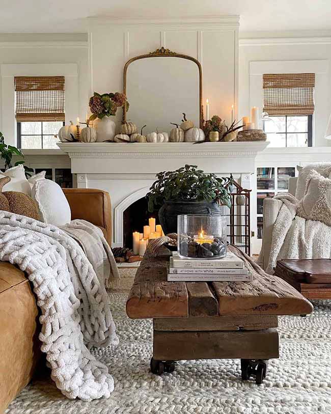 This mantle is stunning with all the tiny white pumpkins and candles. The chunky knit blanket draped over the couch looks incredibly soft and inviting. The rustic wood coffee table is a great contrast to the white fireplace.