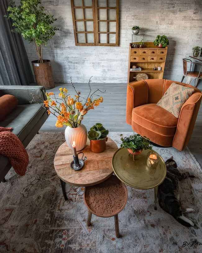 The burnt orange velvet chair is beautiful and looks so comfy. I really like the mix of round wood tables at different heights in the middle of the room. The fresh orange flowers add a nice pop of life.
