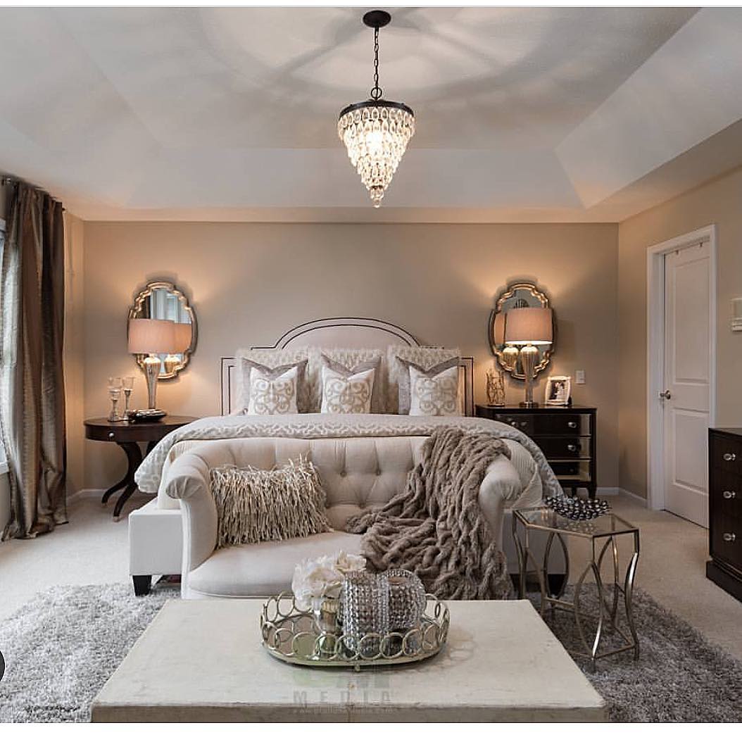 What a glamorous master suite! A large tufted cream sofa with a fluffy brown throw acts as a comfortable divide, establishing a chic sitting area right in front of the bed.