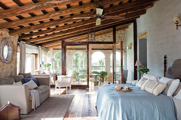 Imagine waking up in this incredible rustic villa! The spacious bedroom naturally flows into a full sitting area with a comfortable gray sofa, separated by the beautiful wooden archways and the amazing terracotta roof structure.