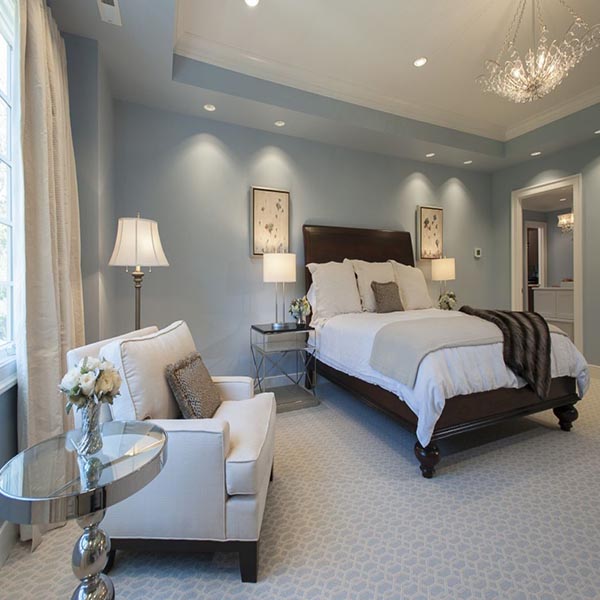 Soft lighting and pale blue walls create such a serene ambiance here. A single, crisp white armchair and a polished silver side table establish a simple yet elegant sitting nook, offering a quiet, private spot for contemplation.