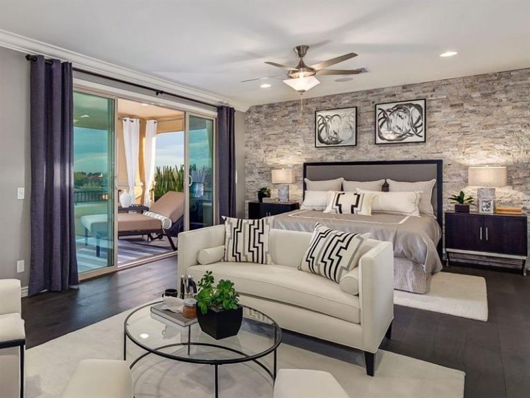 A dedicated living space is established by the sleek white sofa and glass table, positioned between the bed and the huge sliding doors to the patio—a perfect setup for both sleeping and lounging.