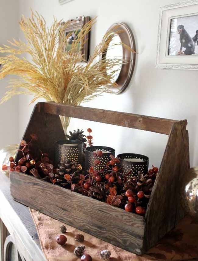 Rustic Centerpiece. This old wooden box is filled with autumn treasures like pinecones and bright red berries. The black candle holders add a cozy, glowing warmth against the light background. This simple arrangement is a perfect, rustic way to celebrate the season.