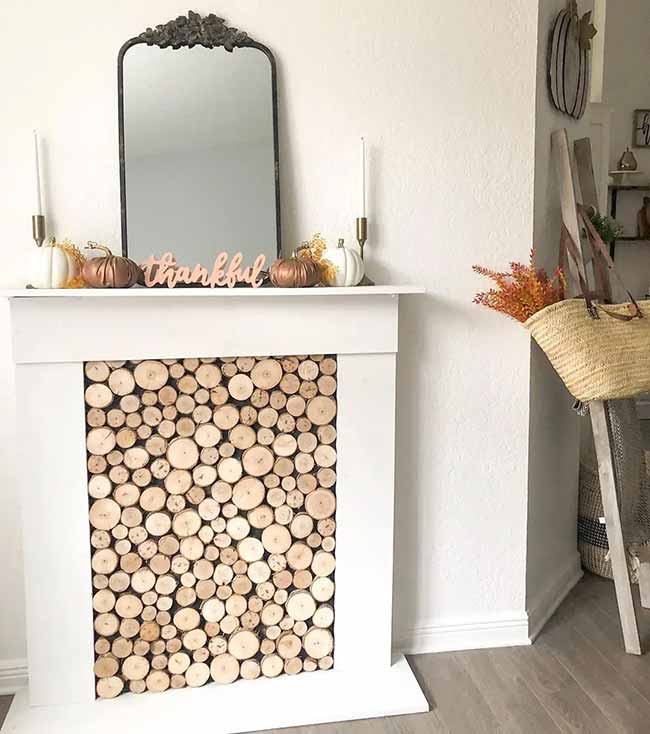 Modern Mantelpiece. I really like how they filled the fake fireplace opening with many round pieces of cut wood; it's a smart and earthy look. The mirror and the word 