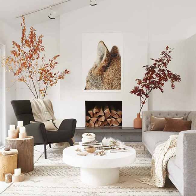 Autumn Leaves Indoors. Bringing big, colorful autumn branches inside is a great way to add fall colors to a white room. The dark chair and wood slices for a table add a strong, natural feel to the space.