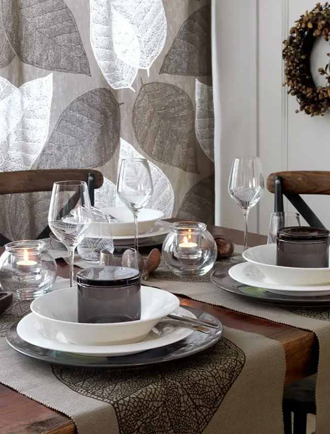Leafy Dining Table. The big leaf pattern on the curtain and table runner sets a nice, natural mood for dinner. The little candles in the smoked glass jars look warm and cozy on the table setting.