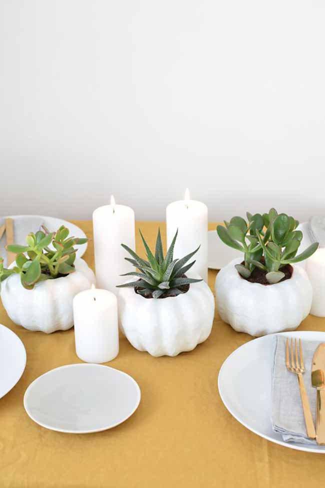 Succulent Centerpiece. These white ceramic pumpkins are a great, modern way to hold small green plants. The gold tablecloth and cutlery make the simple white candles and plants look fancy.