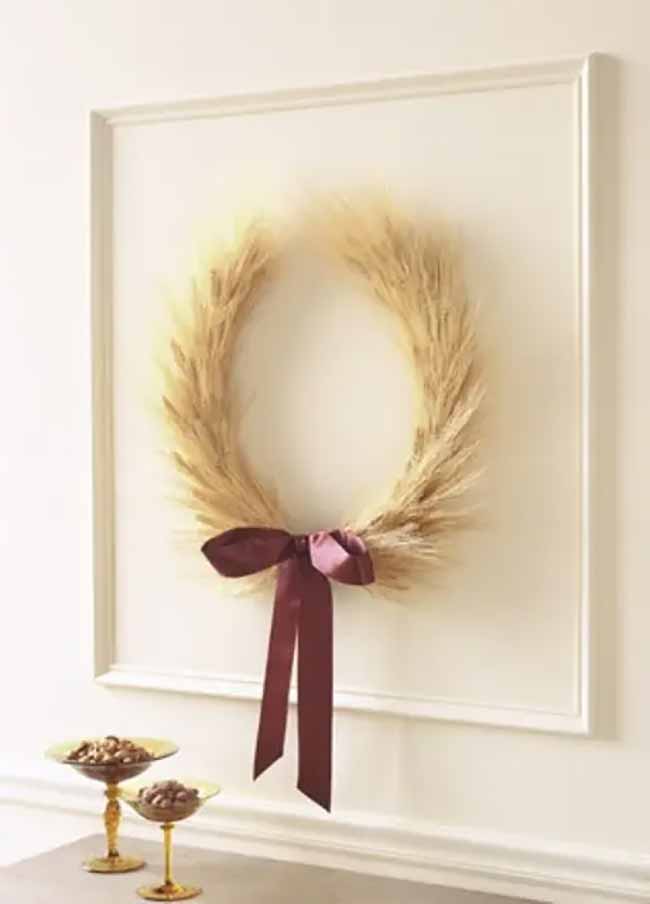 Wheat Wreath. This wreath made of dried wheat looks so warm and simple against the bright white wall. The dark red bow is a perfect color for the autumn season.