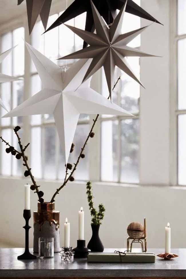 Hanging Paper Stars. The large paper stars hanging in the window are a beautiful and clean decoration. The candles and simple branches on the table below create a lovely, warm light.