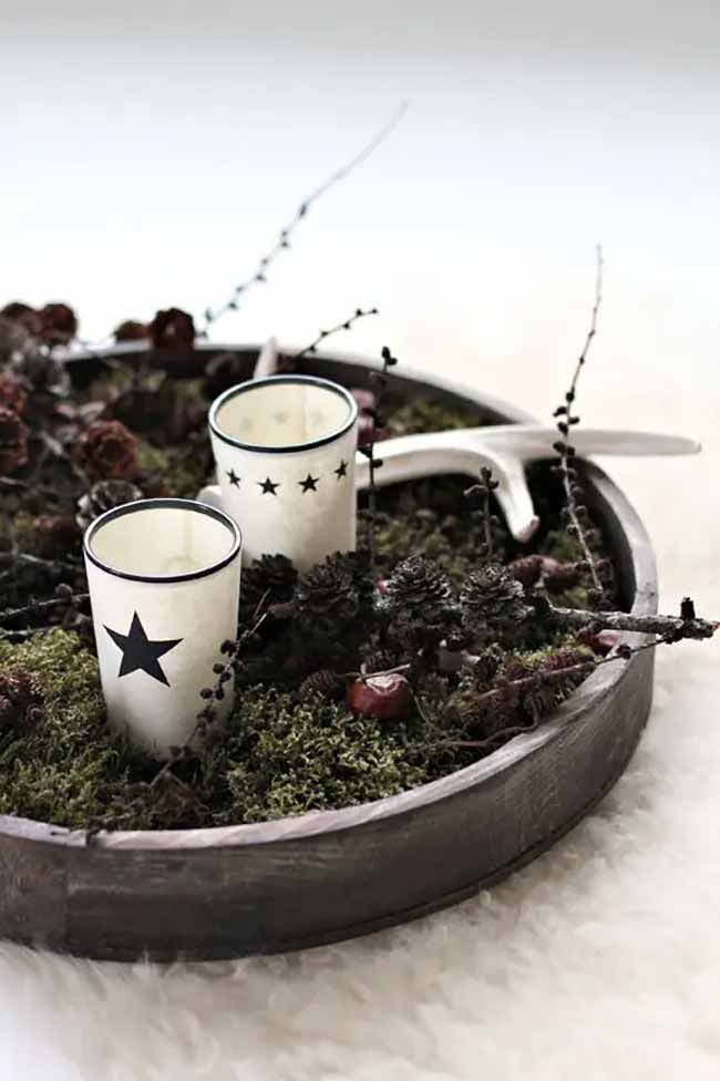 Woodland Tray. This large wooden tray is filled with green moss, pinecones, and even an antler for a true forest look. The little white candle holders with black stars are so charming and simple.