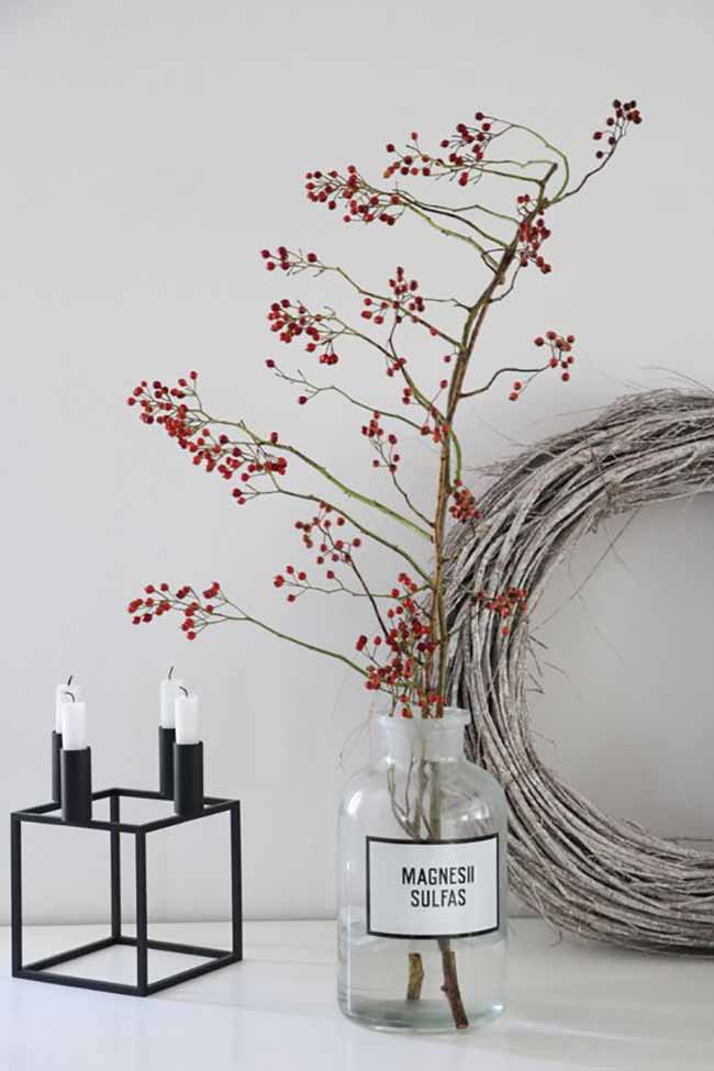 Red Berry and Wreath. The bright red berries in the clear jar look beautiful next to the large gray branch wreath. The sharp black candle holder gives a modern touch to the whole, rustic setup.