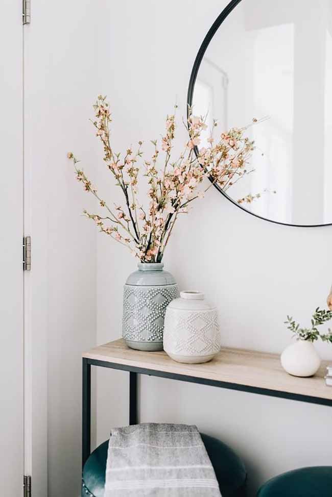 Textured Vases. These vases have cool textured patterns on them that look like beautiful hand-knitting. The small pink flowers bring a bit of softness next to the large black round mirror.