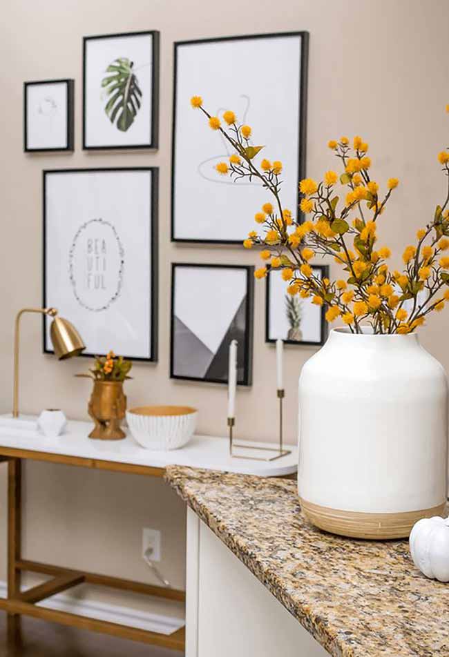 Yellow Blooms and Gallery Wall. A striking black and white gallery wall provides a clean, modern background. Bright yellow flowers in a white vase inject a vibrant pop of autumn color.